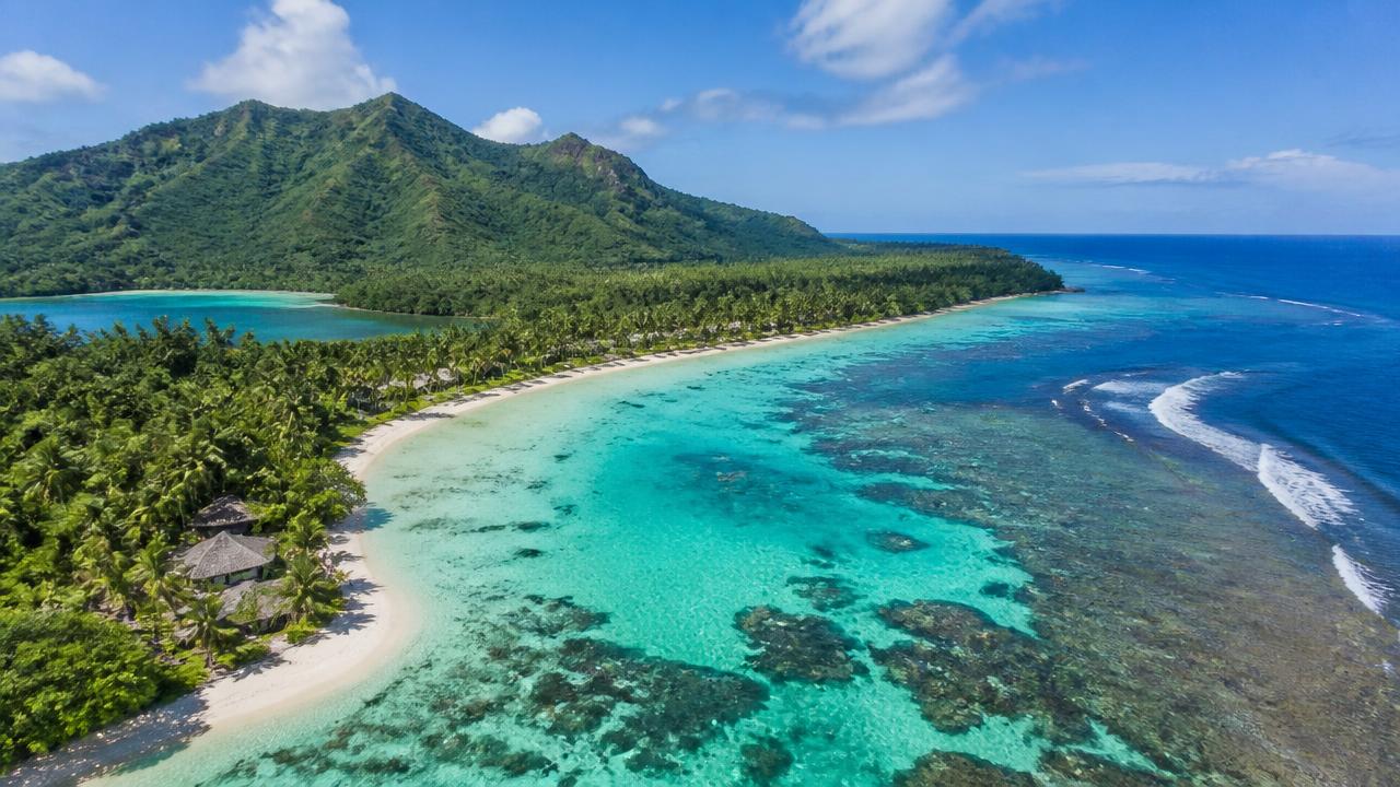 Aerial view of a Vanuatu island with turquoise lagoon, reef and palm-lined beach